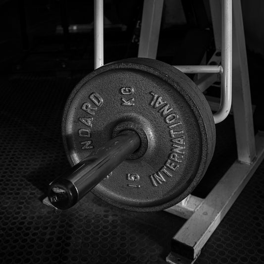 Barbell with weight plate on a rack in a gym setting